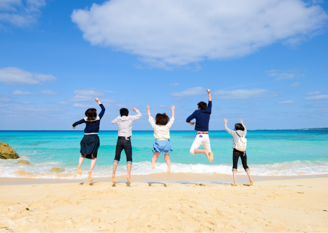 沖縄の海でジャンプする男女グループ